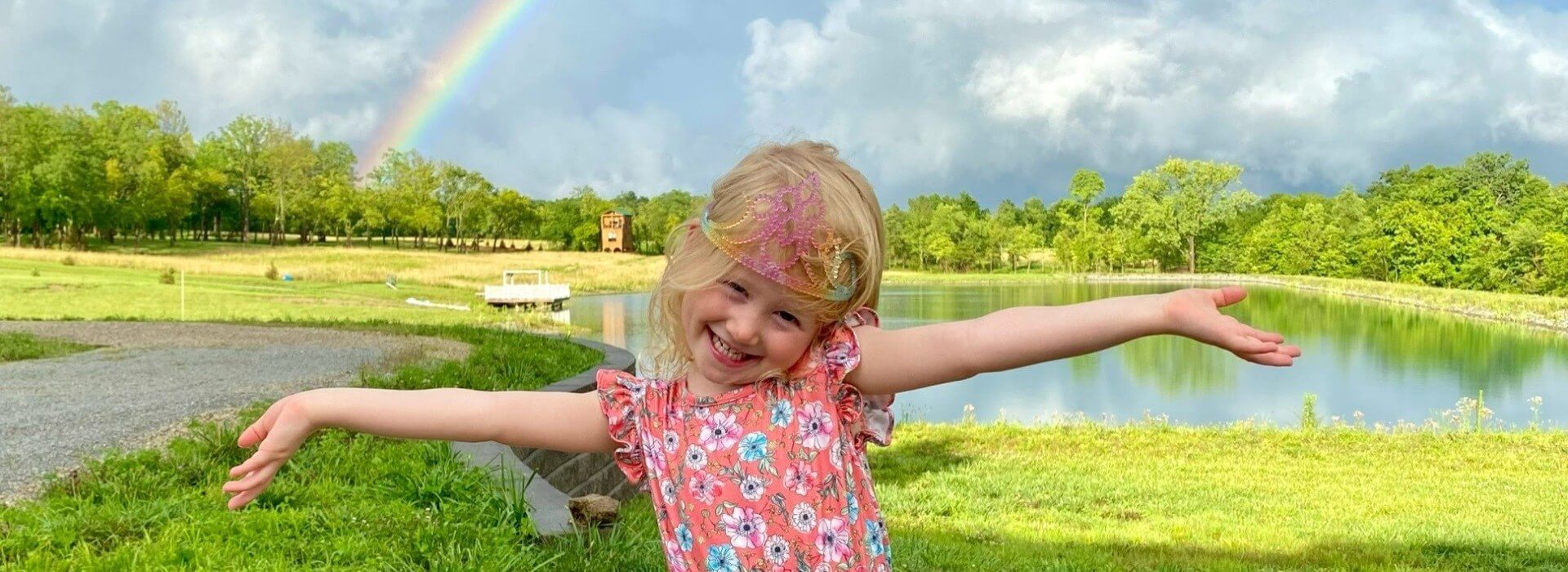 Happy girl wearing princess crown in front of Cedar Shack